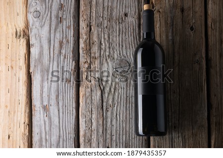 Elegant dark bottle of fragrant red wine on rustic wooden background. Advertising and promotion concept. Mock up. Flat lay. View from above. Space for text.