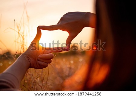 New year planning and vision concept, Close up of woman hands making frame gesture with sunset, Female capturing the sunrise. Royalty-Free Stock Photo #1879441258