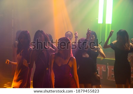 Silhouette image of people dance in disco night club to music from DJ on stage . New year night party and nightlife concept .