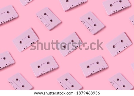 Pattern made with retro audio cassettes on modern pink background. Creative concept of retro technology. 70's or 80's aesthetic. Flat lay, top view.