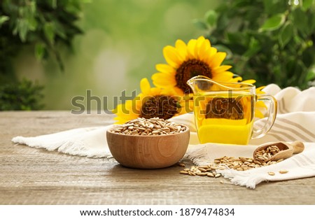 Sunflower oil and seeds on wooden table against blurred background, space for text