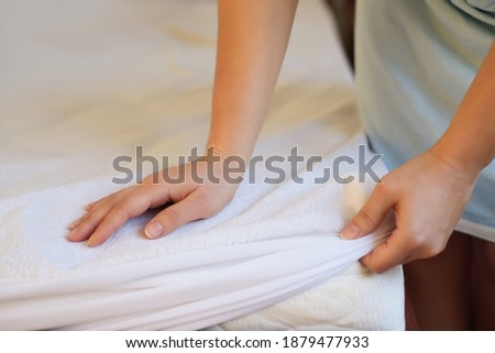 Woman puts a cover on the mattress to protect it from water and house dust mites Royalty-Free Stock Photo #1879477933