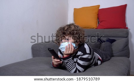 Europe, Italy , MIlan - Child boy 6 years old watching television   during Covid-19 Coronavirus lockdown quarantine home