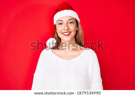 Young brunette woman wearing christmas hat looking positive and happy standing and smiling with a confident smile showing teeth 