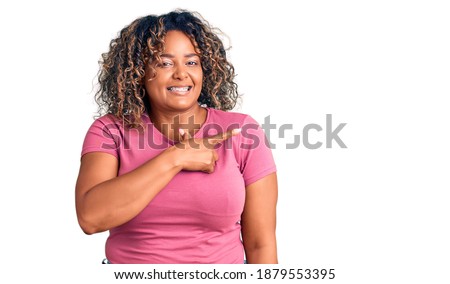 Young african american plus size woman wearing casual clothes cheerful with a smile on face pointing with hand and finger up to the side with happy and natural expression 
