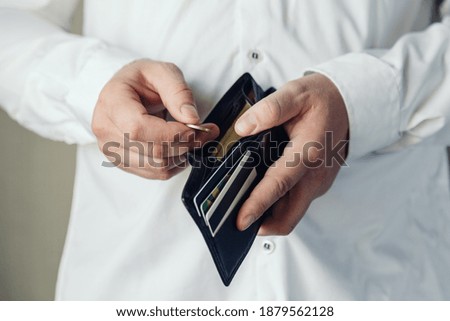 wallet in the hands of a bankrupt man. hand puts one coin. Poverty concept, crisis. dismissal or cost savings