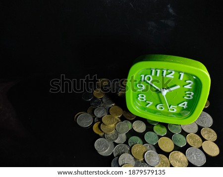Selective focus.Money in front of clock in Business with black background , time and money.Shot were noise and film grain in full resolution.