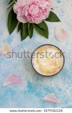 Morning coffee cup concept with pink peony bouquet on blue stone background. Top view. Spring greeting card, wallpapers.