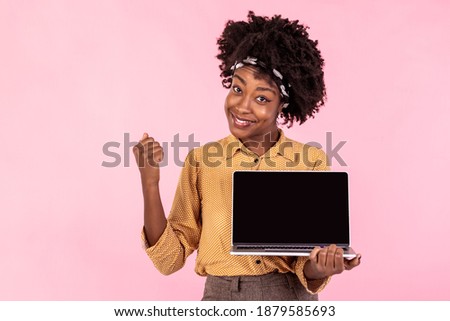 Excited african girl holding laptop with black screen. Happy business woman pointing on the screen of laptop. Advertising concept