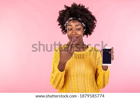 Young woman showing on the telephone. African american woman smiling and covering her mouth with hand giggling. Concept advertising