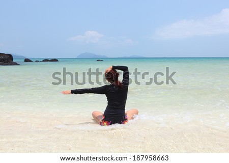 Meditation - Yoga woman meditating at serene beach sunset. Girl relaxing in lotus pose in calm zen moment in the ocean water during yoga holidays resort retreat. Multiracial girl. 
