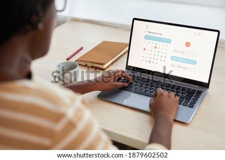 Portrait of young Afriocan-American woman using time management website while using laptop at desk Royalty-Free Stock Photo #1879602502