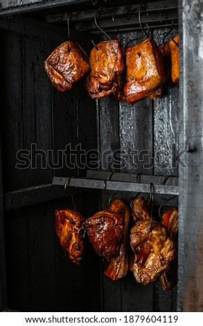 Close up of a smoked meat and belly or beech meat with dark crust in the smokehouse or smoker, food concept Royalty-Free Stock Photo #1879604119