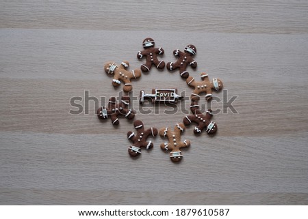 Gingerbread people wearing a mask during the 2020 coronavirus epidemic at Christmas, coperation against Covid-19, Sars-CoV-2, fight together, waiting for vaccination against coronavirus