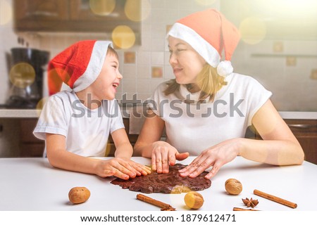 Cooking Christmas and  New Year chocolate cookies or gingerbread. Traditional festive baking, bake with kids. Mom and son in santa hats knead dough. Holiday atmosphere, bokeh