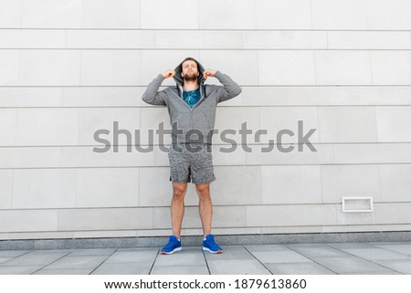 fitness, sport and lifestyle concept - young man in earphones listening to music outdoors