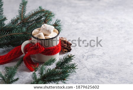 Cup of coffee, hot chocolate or cocoa with marshmallows in a red knitted scarf, branches of a Christmas tree, white table with copy space