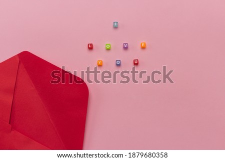 red envelope and the inscription "I love you" from letters, top view, flat way