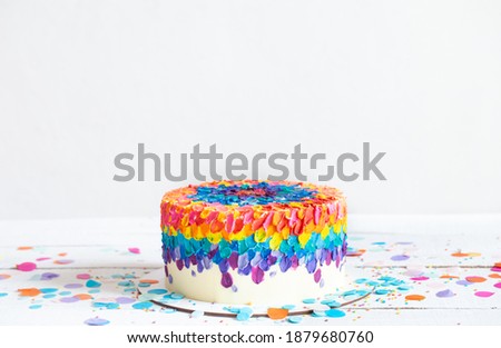 Multicolored birthday cake decorated with cream. Birthday party concept.
