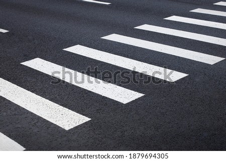 pedestrian crossing, white stripes on black asphalt, road markings zebra crossing, place to cross the road, traffic rules Royalty-Free Stock Photo #1879694305