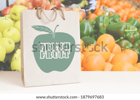 Recycled paper shopping bag in a fresh fruit shop, against some fruits on shelves. Empty copy space for Editor's text.