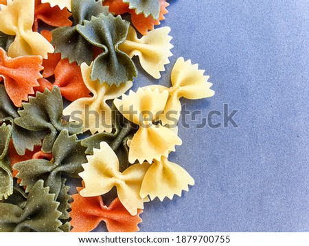 Italian pasta pattern on a grey background. Various colors of bow tie farfalle pasta viewed from above. Top view. Royalty-Free Stock Photo #1879700755