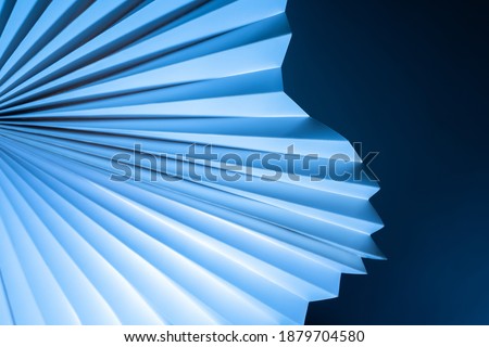 Blue-white three-dimensional background. Paper fan pattern on dark background. Geometric background with a three-dimensional cardboard object. Sometimes blurred abstract image.