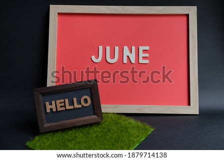 Hello June word wooden in frame on black background. Business, weekend, holiday or new year planning concept.
