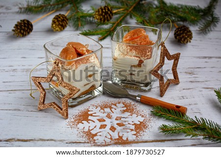 Delicate curd dessert with tangerines in a glass on a light wooden table in the Christmas decor. New Year's treats concept. Top view