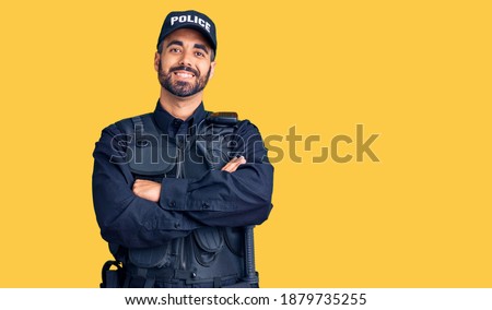 Young hispanic man wearing police uniform happy face smiling with crossed arms looking at the camera. positive person. 