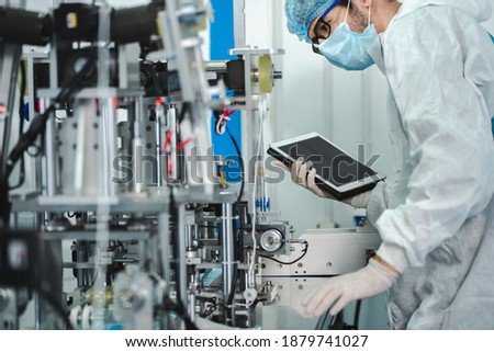 Medical mask factory, a team of medical professionals, a wide range of industries, programming and manipulation of high-tech facility robots Scientist Sterile clothing, lab work Royalty-Free Stock Photo #1879741027