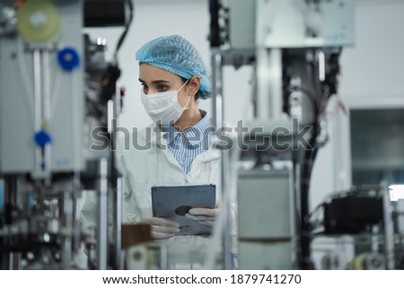 Medical mask factory, a team of medical professionals, a wide range of industries, programming and manipulation of high-tech facility robots Scientist Sterile clothing, lab work Royalty-Free Stock Photo #1879741270