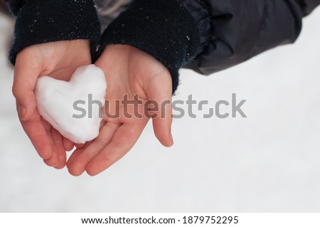Heart made of snow in children's hands on a white background Royalty-Free Stock Photo #1879752295