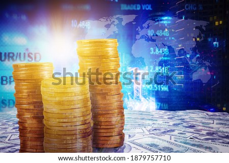 Close up of heaped gold coins over banknotes with double exposure of modern city and stock trading background