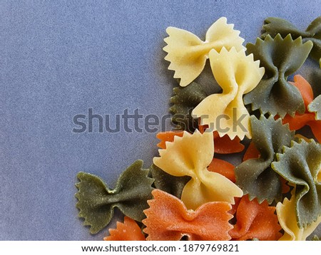 Dry colorful Italian pasta farfalle or bows on grey background. With copy space  Royalty-Free Stock Photo #1879769821
