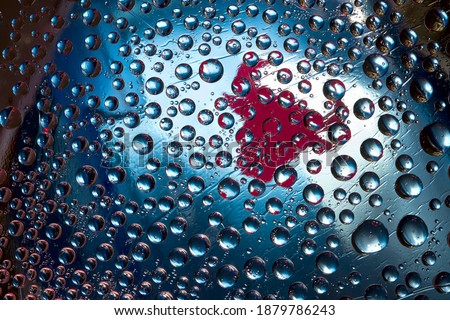 Multi colored drops of water are located on a blue mirror background with a red silhouette of a bull. Abstract fantasy. 3D render.