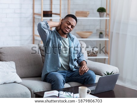 Neck Pain. African American Man Massaging Aching Neck Suffering From Ache Sitting And Working At Laptop On Couch In Living Room At Home. Osteoarthritis, Health Problem Concept. Royalty-Free Stock Photo #1879806703
