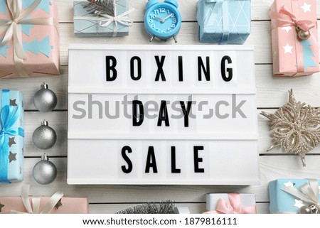 Flat lay composition with Boxing Day Sale sign and Christmas gifts on white wooden table