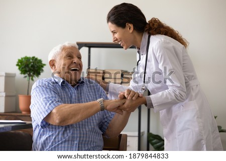 Positive young female nurse have fun laugh and joke with happy elderly male patient at consultation in hospital. Caring woman doctor support cheer and comfort mature man. Good medicine concept. Royalty-Free Stock Photo #1879844833