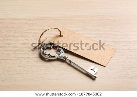 Key with blank tag on wooden table. Keyword concept