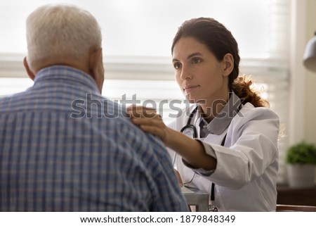 Young Caucasian female nurse touch support unhealthy mature male patient at clinic consultation. Supportive woman doctor comfort show empathy and care to elderly man client in hospital. Royalty-Free Stock Photo #1879848349