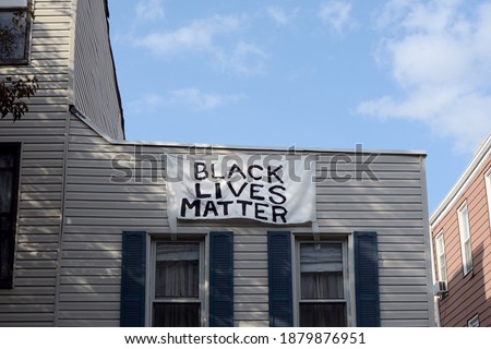 Black Lives Matter Sign Hanging from Residential Building Roof 