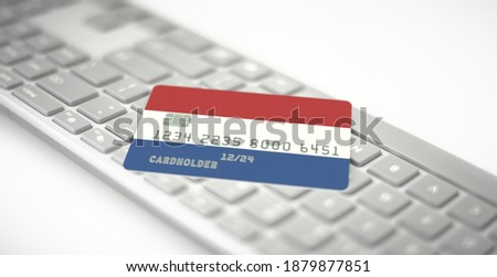 Credit card depicting flag of the Netherlands on computer keyboard. Fictional numbers