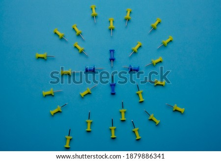 circle of yellow and blue pushpins on blue color background