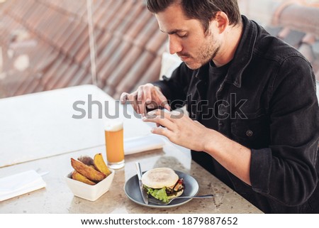A young man taking pictures of his food with a smartphone, concept of a blogger man 