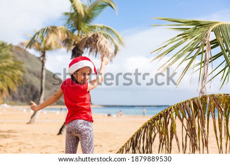 Little adorable girls in Santa hats during beach Christmas vacation