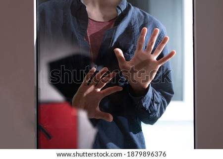 creepy horror scene, person's hands in the dark behind the glass, abstract shadow fear 
