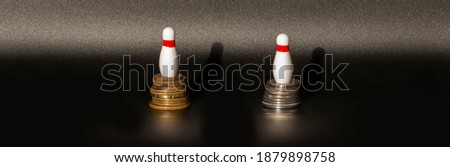 white bowling pins on top of the coins on a black background.Business concept