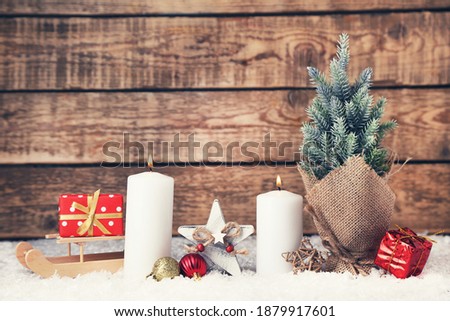 Christmas candles with ornaments and fir tree on brown wooden background