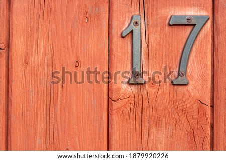 Number 17 as metal digits on rough red wood
